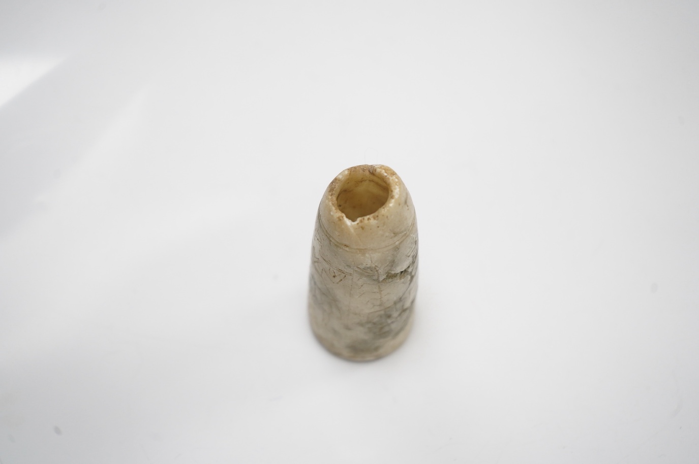 An Egyptian incised alabaster cosmetics bottle (bullet shaped), 7.5cm. Condition - restored